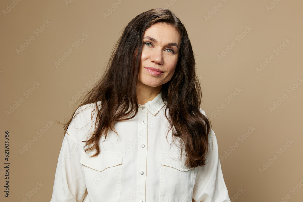 a beautiful horizontal portrait of an adult woman with black hair flowing in the wind standing in a white shirt. Studio photo with an empty space on the background