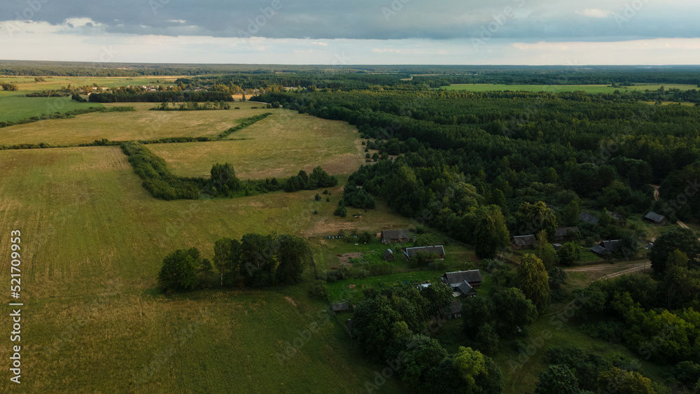 Rural landscape at dawn. Green forests and fields in the rays of the rising sun. Aerial photography.