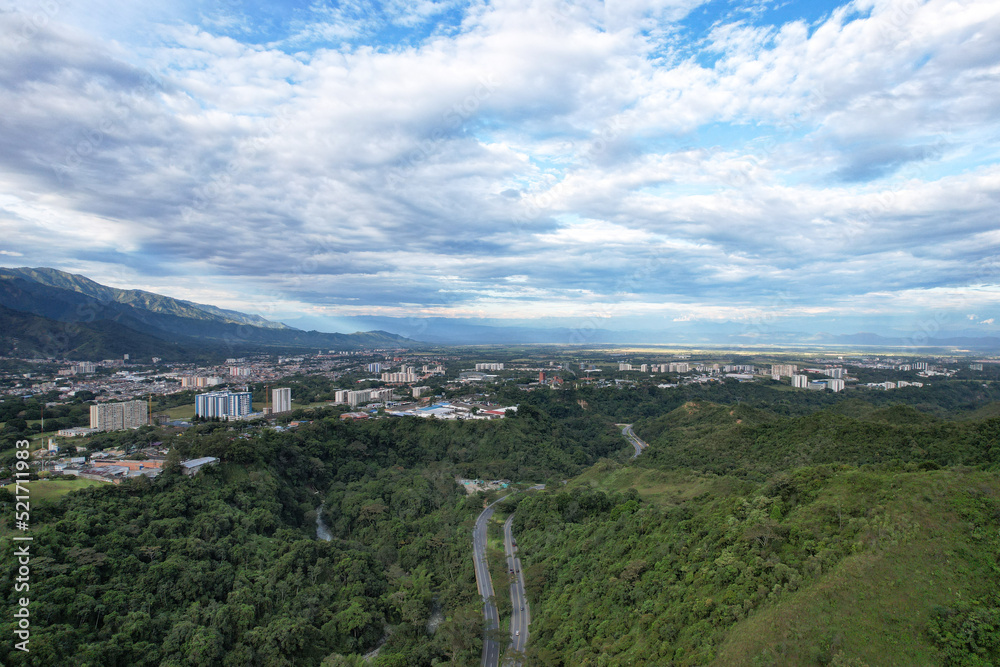 Colombia - Ibague, vista de dron con una montaña, la ciudad de ibague, una carretera en la mitad y un maravilloso cielo.