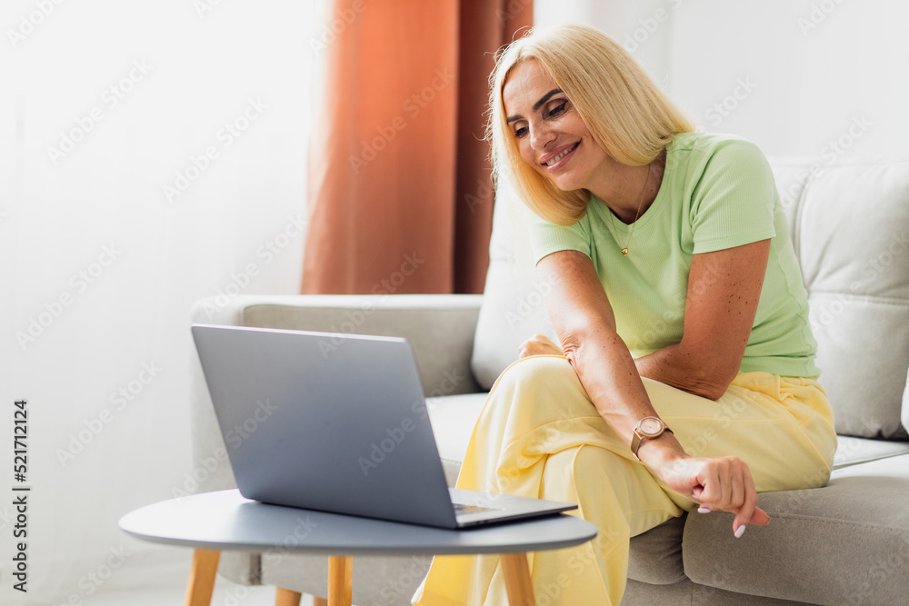 Attractive blonde middle-aged woman uses laptop and video call