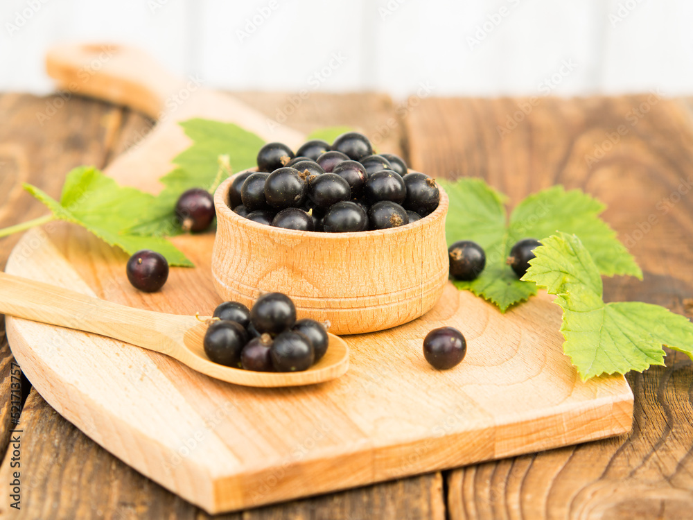 Fresh blackcurrant berries in a bowl on a wooden table near green leaves. Juicy natural currant fruits. Black currant Fresh blackcurrant berries in a bowl on a wooden table near green leaves. Juicy natural currant fruits. Black currant
