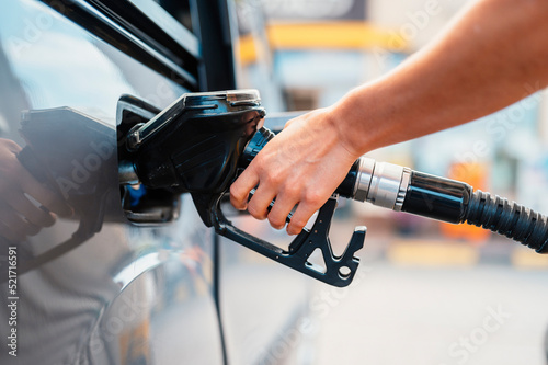 Photographie Closeup of woman pumping gasoline fuel in car at gas station