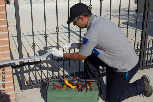 Electrician at work with tools of the trade while assembling and repairing the motor of an automatic gate. Do it yourself homework
