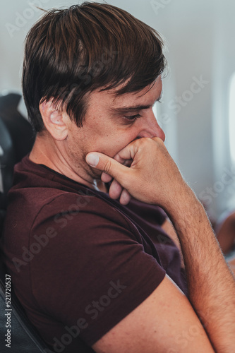 bored thoughtful unshaven people person man with 40+ years with stubble is sitting on a airplane during a flight from the airport to travel. spending time on the air plane. idle and do nothing