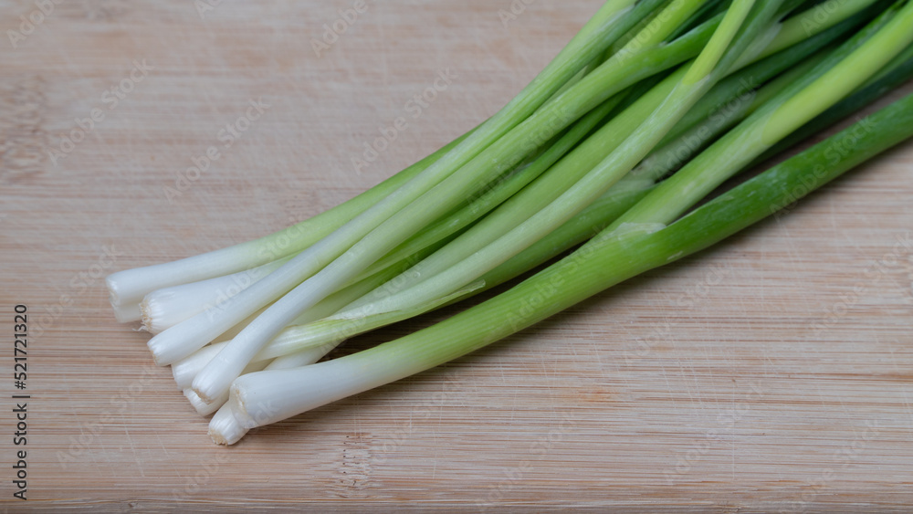 Green onion feathers lie on a wooden board close-up of greens Green onion feathers lie on a wooden board close-up of greens