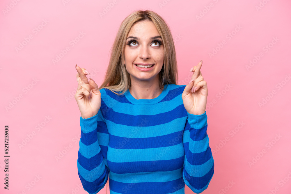 Pretty blonde woman isolated on pink background with fingers crossing and wishing the best Pretty blonde woman isolated on pink background with fingers crossing and wishing the best