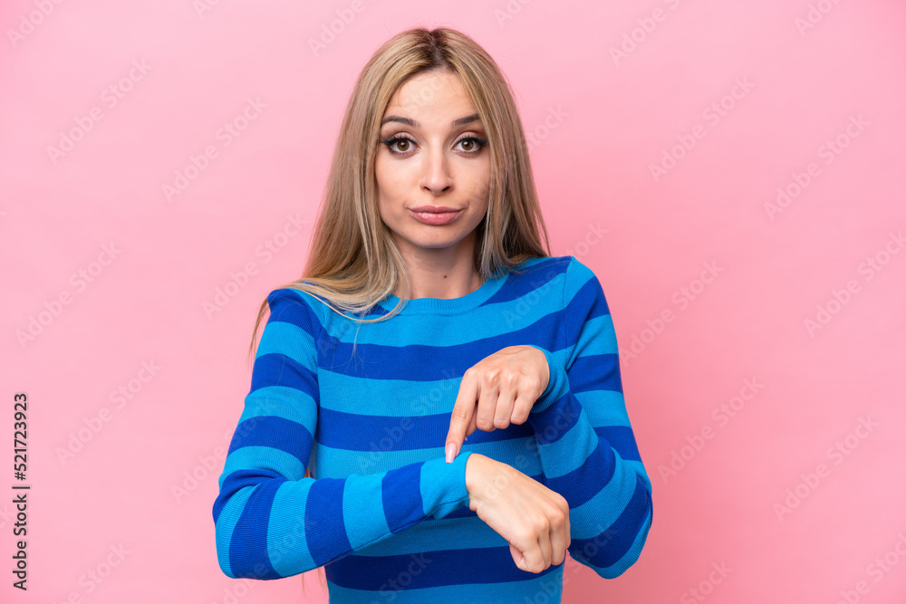 Pretty blonde woman isolated on pink background making the gesture of being late Pretty blonde woman isolated on pink background making the gesture of being late