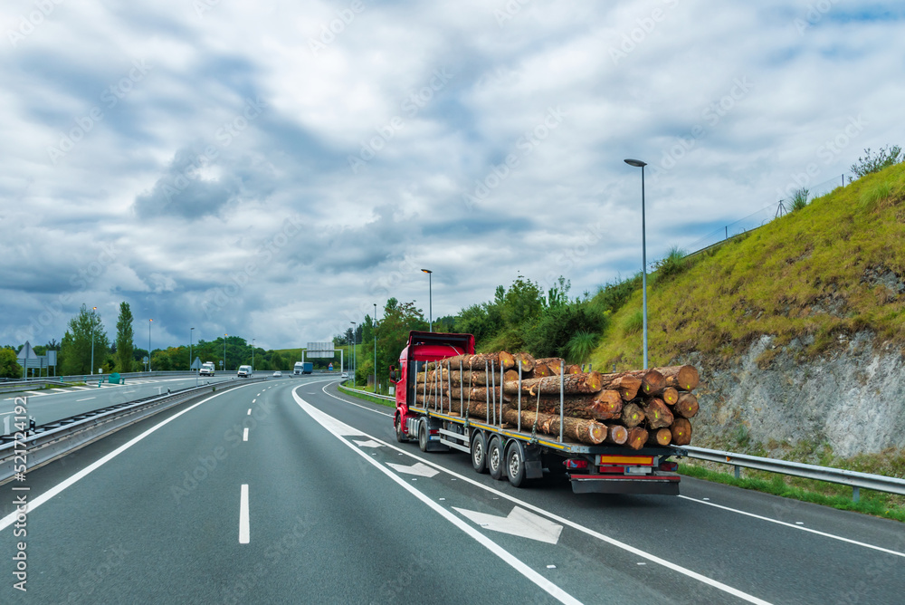Truck loaded with wood logs entering a highway.