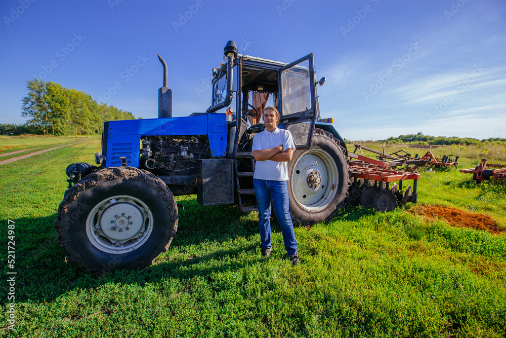 Farmer stands near the tractor on agricultural field Farmer stands near the tractor on agricultural field