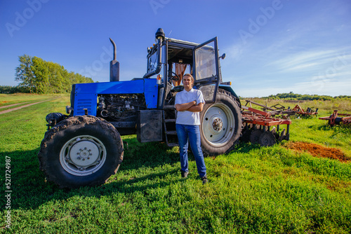 Farmer stands near the tractor on agricultural field