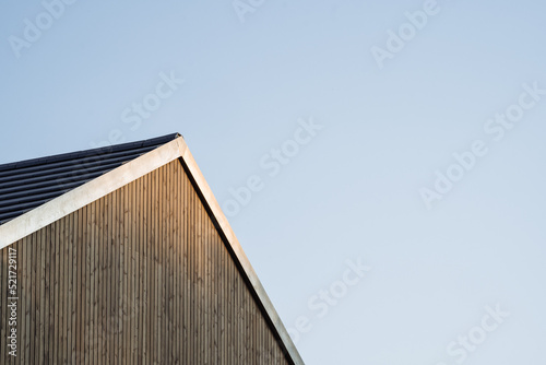 Facade and tood of a modern wooden single family house in the sunset