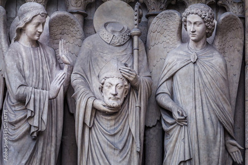 Saint Denis without head and angel, Notre dame detail, Paris, France photo