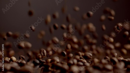 Coffee seeds dawnfall closeup. Roasted beans falling down on table bouncing. photo