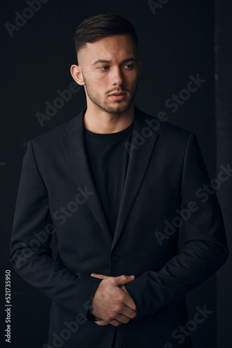 Modelling snapshots. Narcissistic self-confident tanned attractive handsome man in classic suit jacket looks aside posing isolated in over black studio background. Fashion offer. Copy space for ad © SHOTPRIME STUDIO