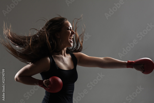 Bild auf Leinwand beautiful girl exercising karate punch and screaming against gray background