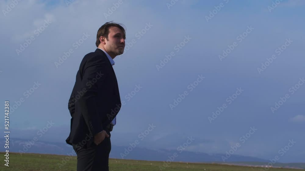 Businessman looking at horizon in field, thoughtful relaxation.
Businessman watching the horizon in the field takes his hands out of his pockets and relaxes by lifting them up.
Businessman looking at horizon in field, thoughtful relaxation.
Businessman watching the horizon in the field takes his hands out of his pockets and relaxes by lifting them up.