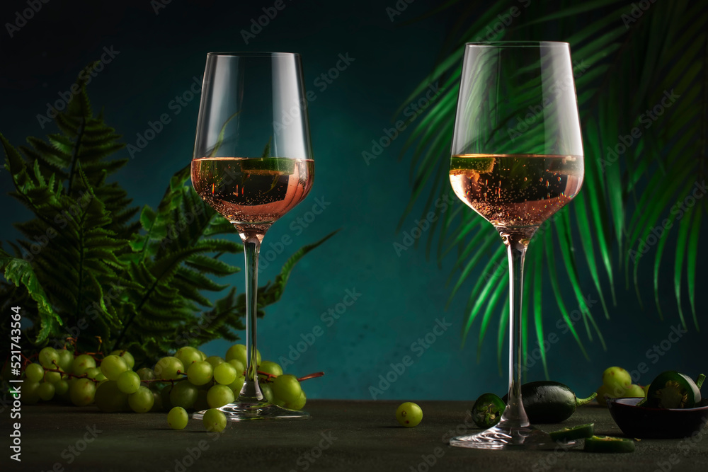 Rose pink wine with jalapeno pepper in wine glass, dark background