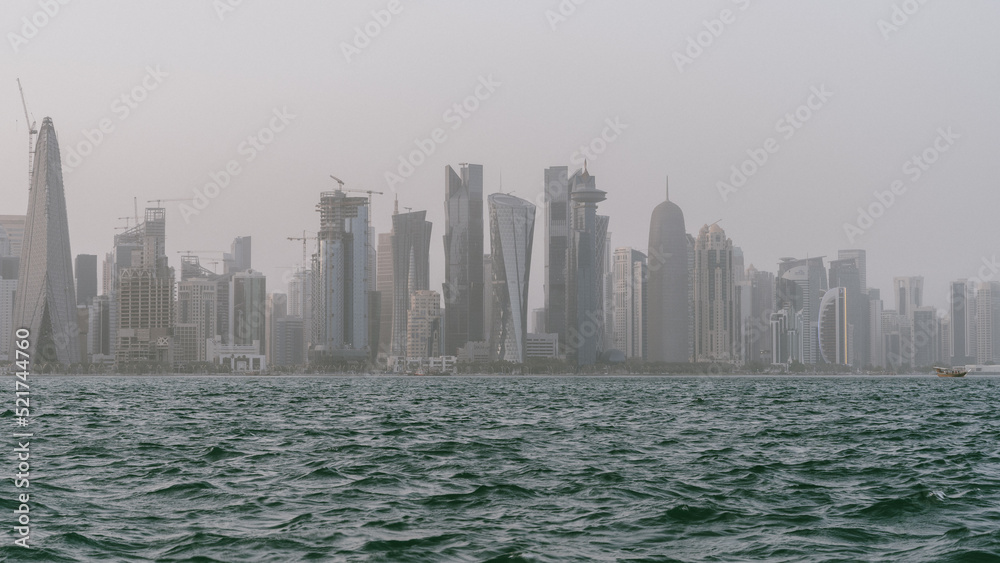 Obraz premium Qatar skyline with rough sea in the foreground on a windy and rainy day.