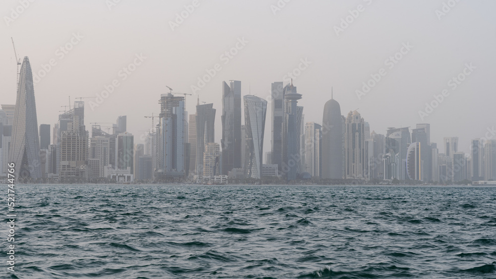 Qatar skyline with rough sea in the foreground on a windy and rainy day.