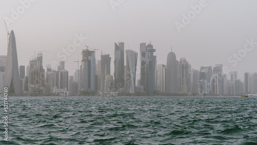 Qatar skyline with rough sea in the foreground on a windy and rainy day.