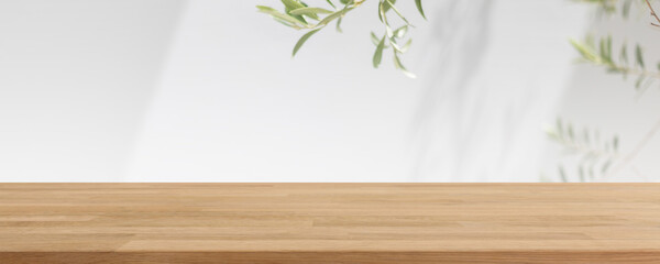 Empty wood table top and blurred white wall in garden background with Green leaves - can used for display or montage your products.