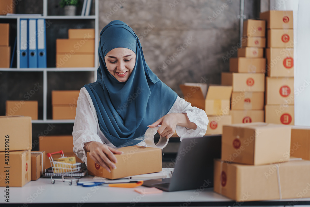 Small Startup Muslim Woman Checking parcels at work, freelancers, salespeople, checking production orders. Pack products to send to customers. Sell Ecommerce Shipping Ideas. Small Startup Muslim Woman Checking parcels at work, freelancers, salespeople, checking production orders. Pack products to send to customers. Sell Ecommerce Shipping Ideas.