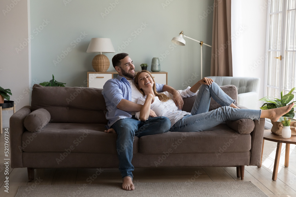 Relaxed couple in love enjoy conversation resting on sofa in fashionable  living room, share dreams, planning future and children, spend time at  modern home. Daydreams, romantic relations, date concept foto de Stock