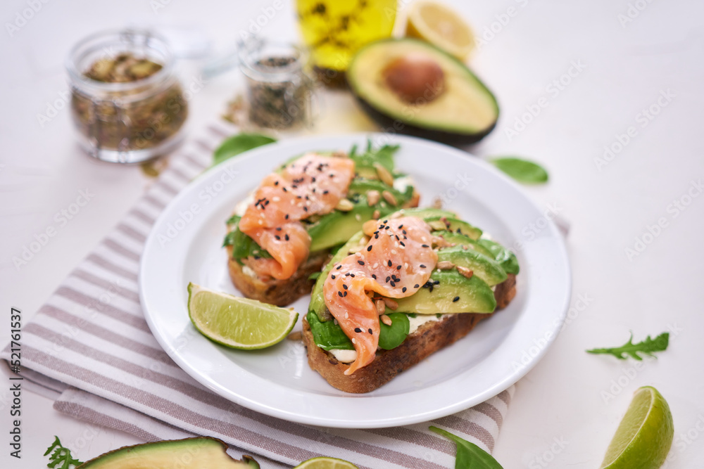 Freshly made Avocado, salmon and cream cheese toasts on a white ceramic plate Freshly made Avocado, salmon and cream cheese toasts on a white ceramic plate