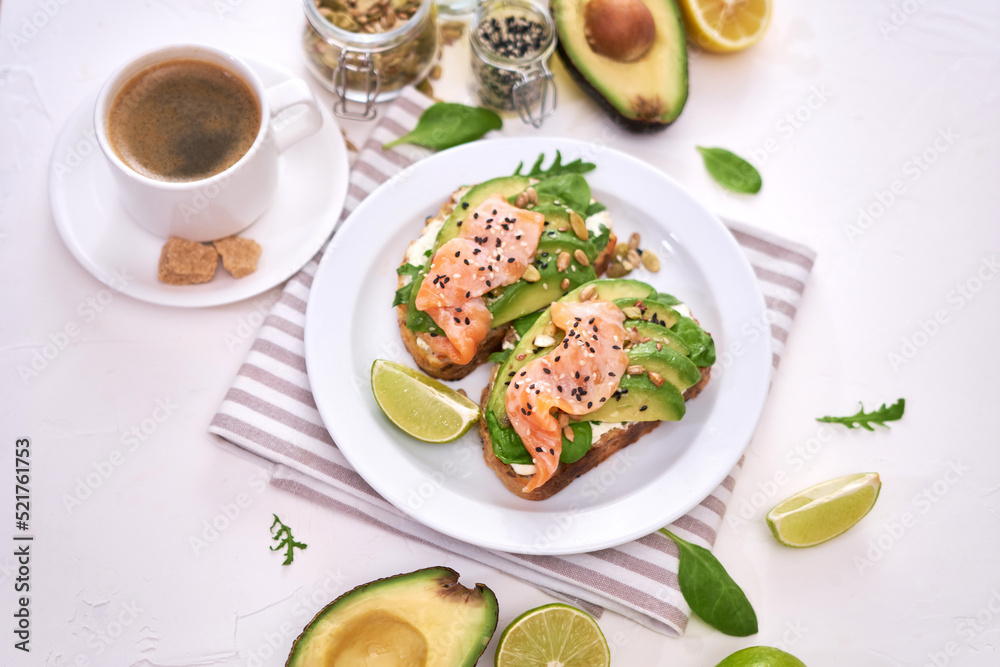 Freshly made Avocado, salmon and cream cheese toasts on a white ceramic plate