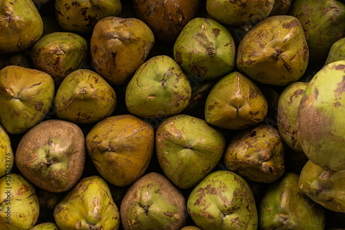 Green coconut fruits, piled on a stall at the bazaar, natrual food background or texture. photo