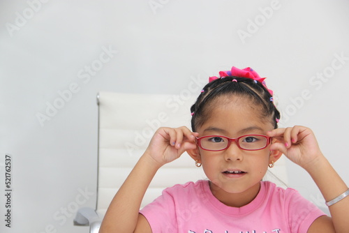 Brunette Latin girl shows her red glasses to see better because she has myopia and astigmatism
 photo
