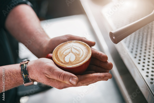 Close up of male Barista hands holding fresh made cappuccino or latte cup in coffee shop