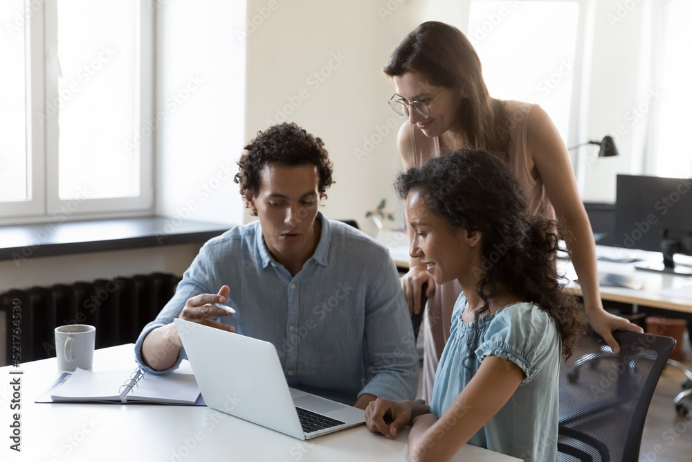 Three diverse colleagues, office employees discussing strategy, working on project together, involved in briefing, brainstorming using laptop. Cooperation, collaborative task, team-work, tech concept