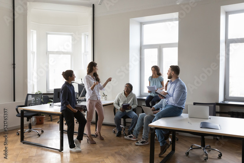 Multiethnic work group talk at meeting, discuss business ideas, sharing creative thoughts. Diverse colleagues office employees speaking negotiating at informal briefing at modern co-working workplace