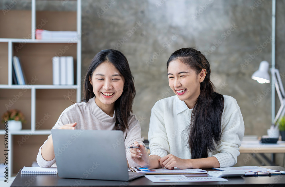 Two Asian businesswomen use laptops and smartphones in an open space office. Business concept. Data analysis, roadmap, marketing, accounting, auditing. Two Asian businesswomen use laptops and smartphones in an open space office. Business concept. Data analysis, roadmap, marketing, accounting, auditing.