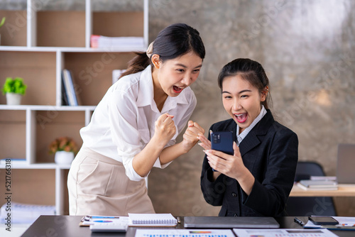 Team work process Two women are immensely delighted, Yes, having succeeded with a smartphone in an open office. business idea Data Analysis, Roadmap, Marketing, Accounting, Auditing photo