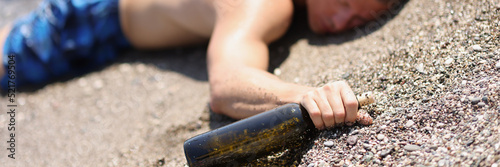 A drunk man with a bottle lies on the wet sand, blurry photo