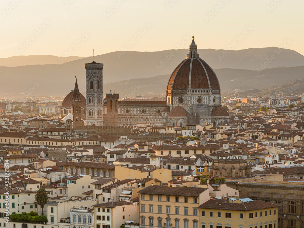 Gothic Florence's cathedral, the Duomo,  named in honor of Santa Maria del Fiore, Italy, Tuscany turns off above the roofs of nearby houses, at summer sunset
