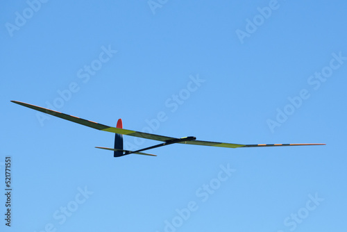 A high performance remote-controlled glider of the F5J competition class with an electric motor  flying in the blue summer sky.