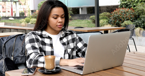 Photo portrait of gorgeous attractive woman working on laptop typing sitting in cafe drinking coffee