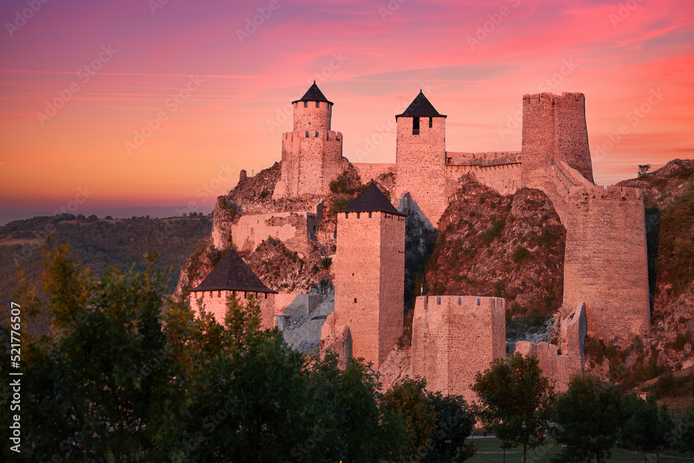 The medieval fortress of Golubac illuminated of pink light of setting sun against colorful clouds in background. Famous tourist place, Serbia.