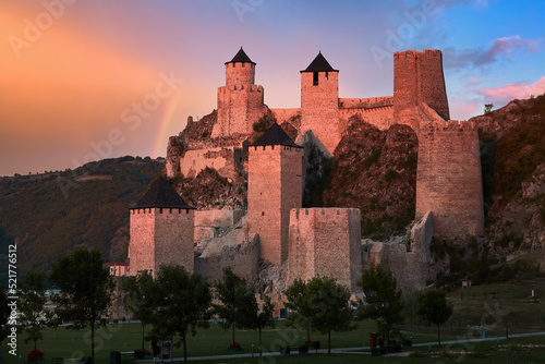 The medieval fortress of Golubac, fortress towers illuminated of pink light against a rainbow and colorful clouds in background. Famous tourist place, Serbia. photo