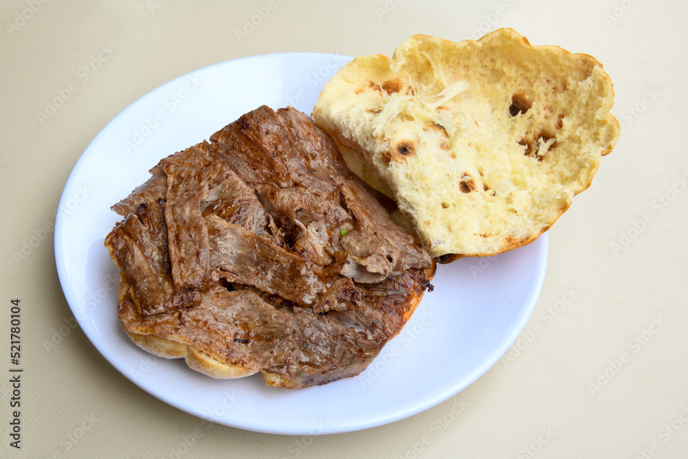 Turkish and Arabic Traditional Ramadan doner kebab with tasty tomato sauce and rice or turkish pilav in white plate on wood table background. ( , Iskender, ekmek arasi pilav ustu doner, doner durum ) Turkish and Arabic Traditional Ramadan doner kebab with tasty tomato sauce and rice or turkish pilav in white plate on wood table background. ( , Iskender, ekmek arasi pilav ustu doner, doner durum )