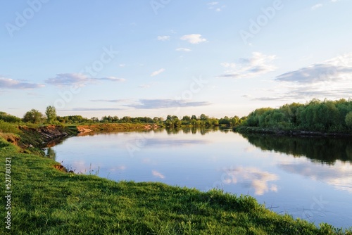 summer landscape with a river, clouds are reflected in the water surface
