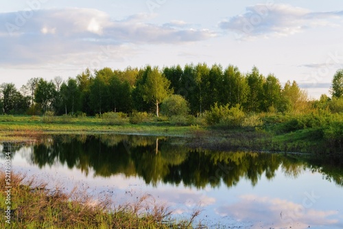 summer landscape with a river, clouds are reflected in the water surface