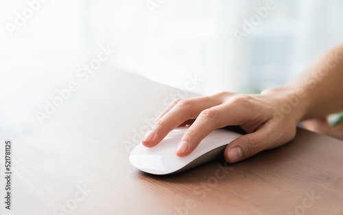 Hand using white mouse on the wood table.