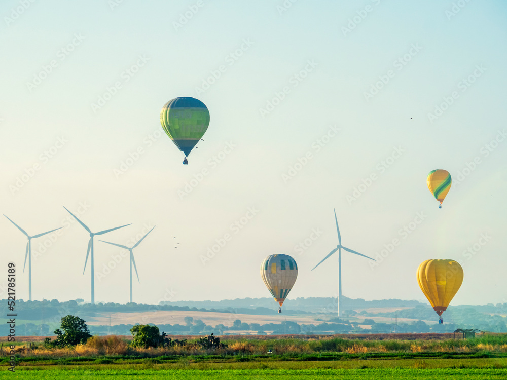 Obraz premium Globos aerostáticos volando sobre una instalación eólica en Cadiz
