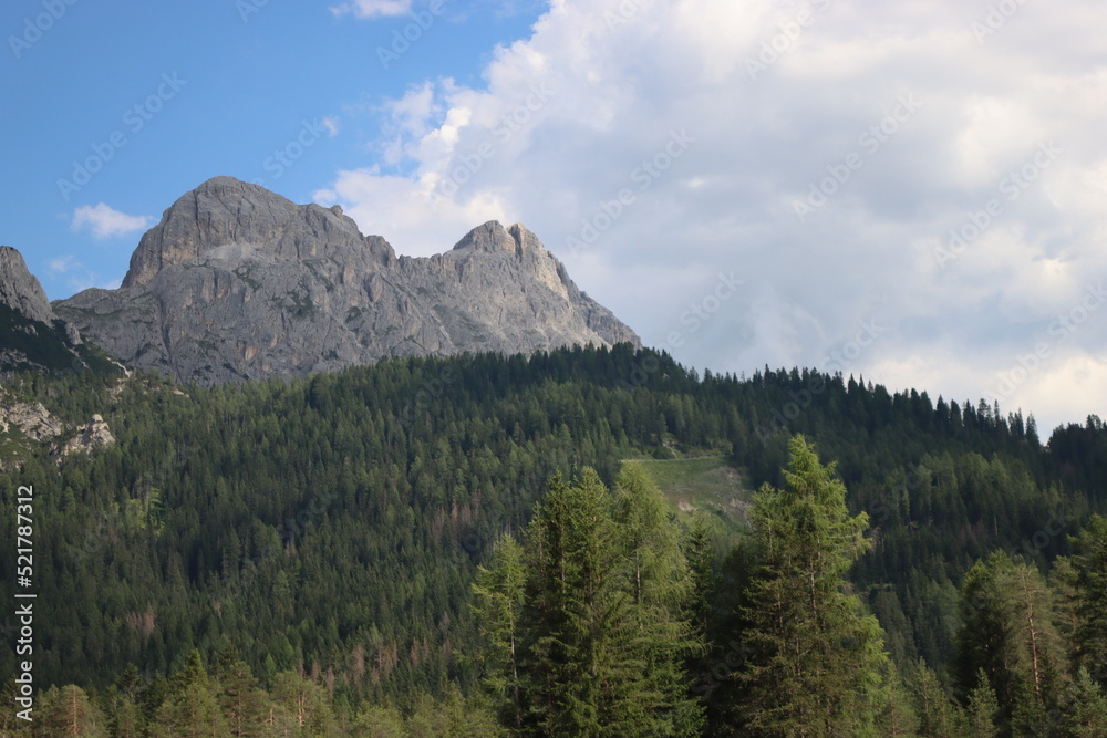 Fototapeta premium Coravara, Italy-July 16, 2022: The italian Dolomites behind the small village of Corvara in summer days with beaitiful blue sky in the background. Green nature in the middle of the rocks.