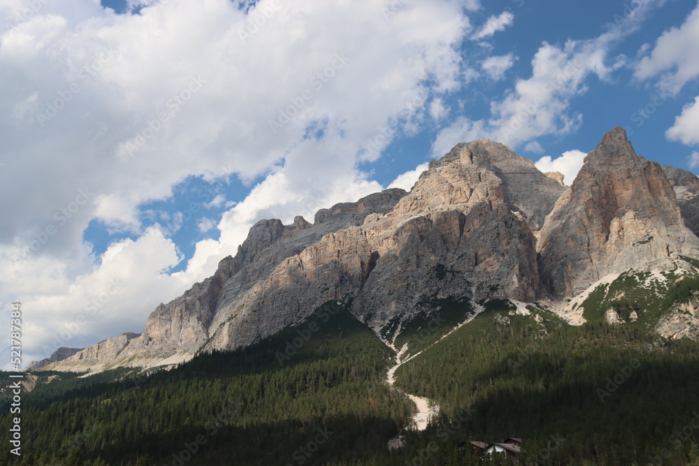 Coravara, Italy-July 16, 2022: The italian Dolomites behind the small village of Corvara in summer days with beaitiful blue sky in the background. Green nature in the middle of the rocks.
