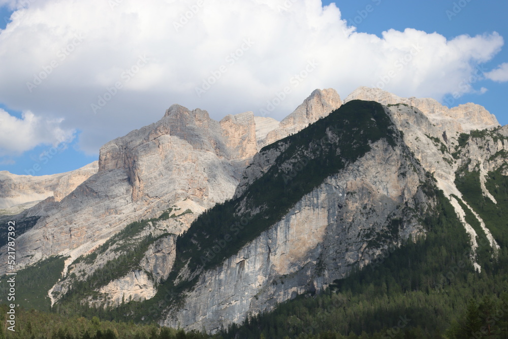 Coravara, Italy-July 16, 2022: The italian Dolomites behind the small village of Corvara in summer days with beaitiful blue sky in the background. Green nature in the middle of the rocks. Coravara, Italy-July 16, 2022: The italian Dolomites behind the small village of Corvara in summer days with beaitiful blue sky in the background. Green nature in the middle of the rocks.